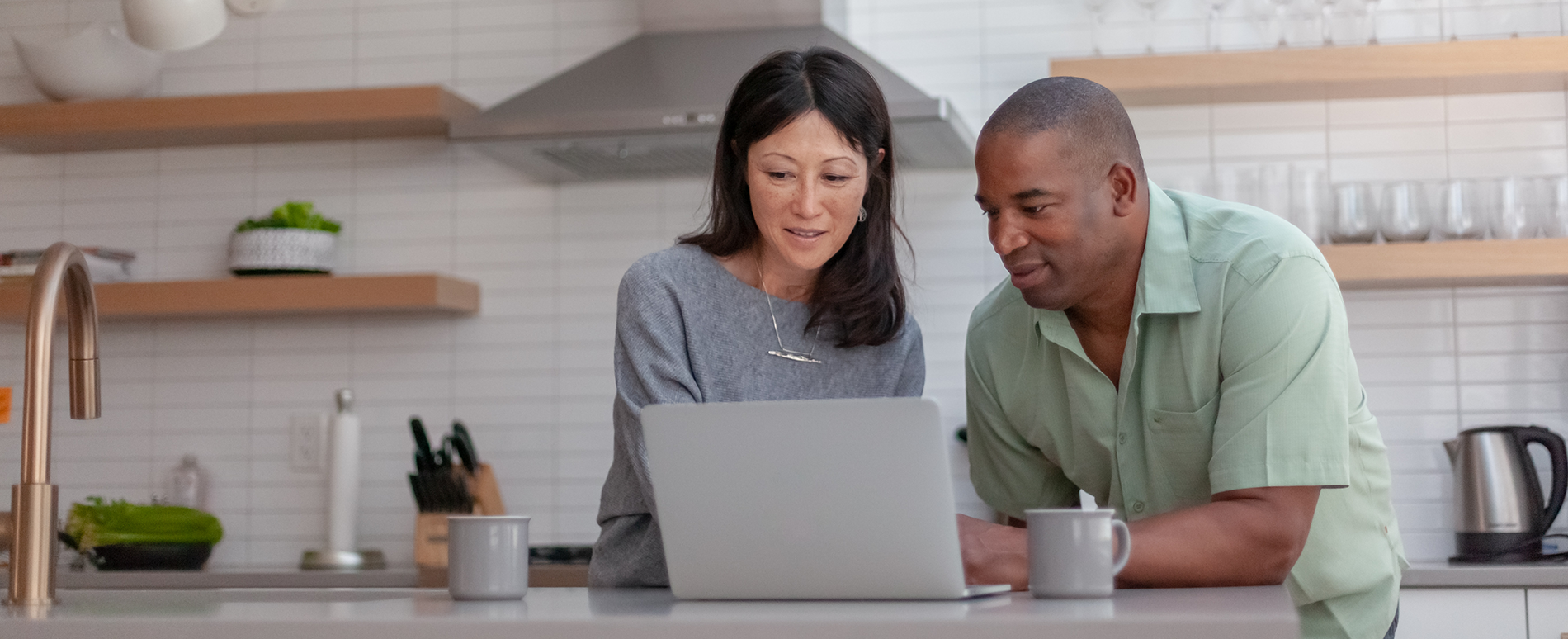 A couple uses a laptop in their kitchen